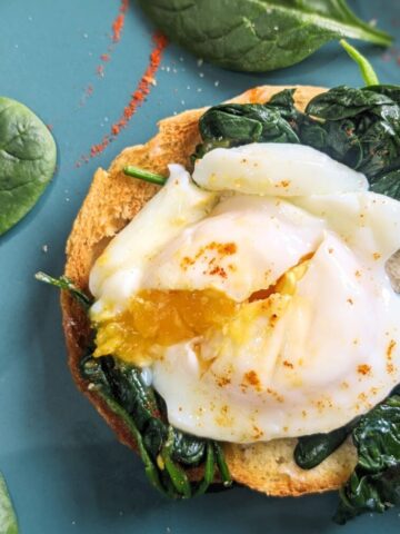 A poached egg with wilted spinach on a slice of toast.