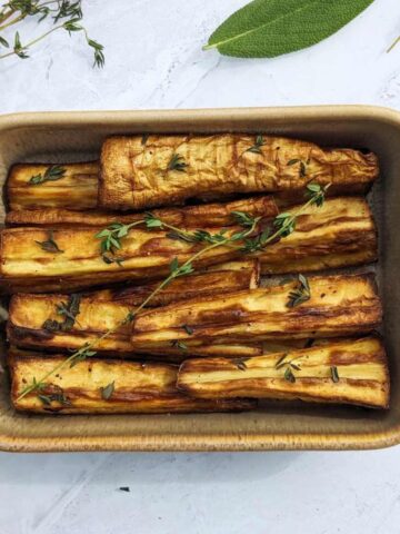 Air fryer parsnips in a serving dish with fresh herbs scattered on top.