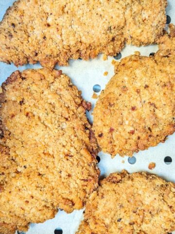 Chicken tenders on an air fryer basket.